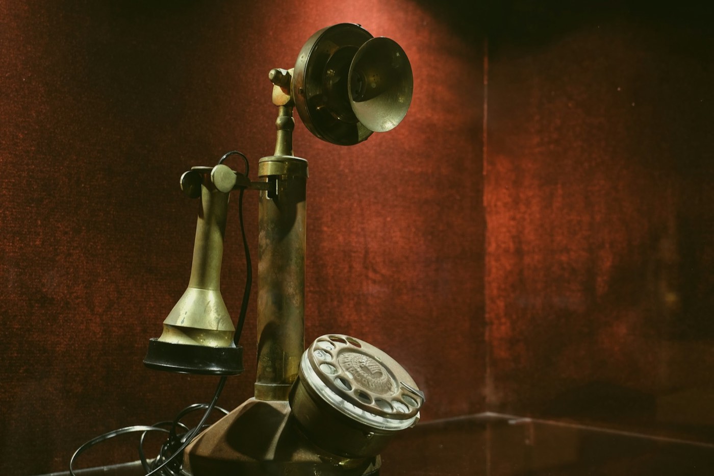 Altes Messingtelefon vor dunkelrotem Hintergrund